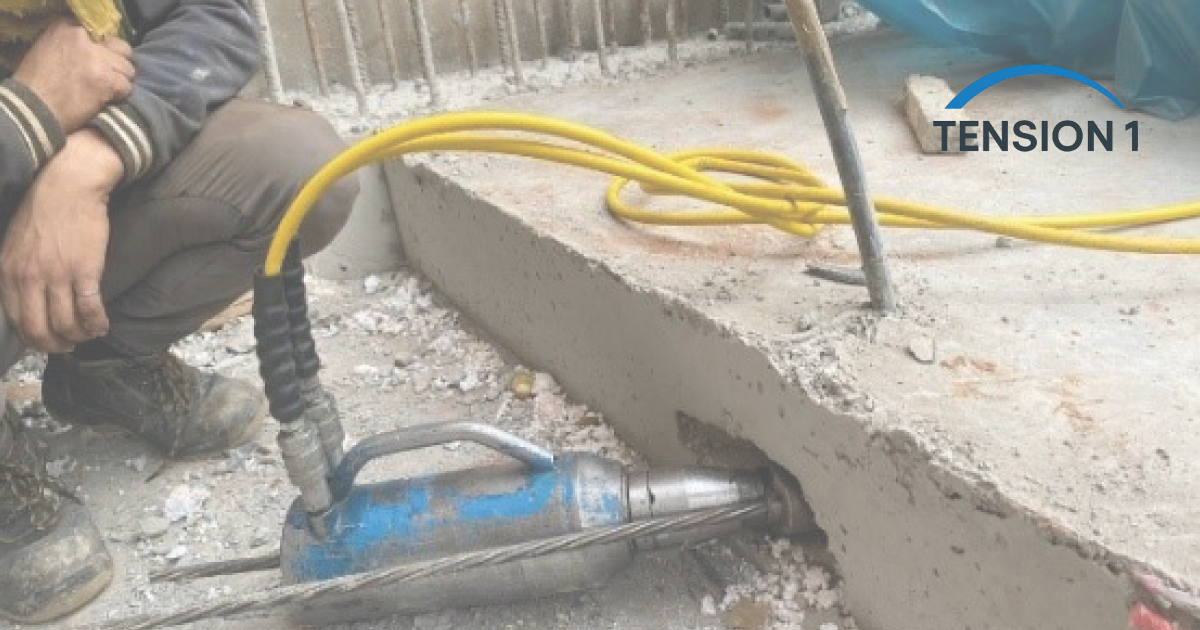 A construction specialist inspecting a post-tension slab edge during a hydraulic jack cable stressing procedure on-site.